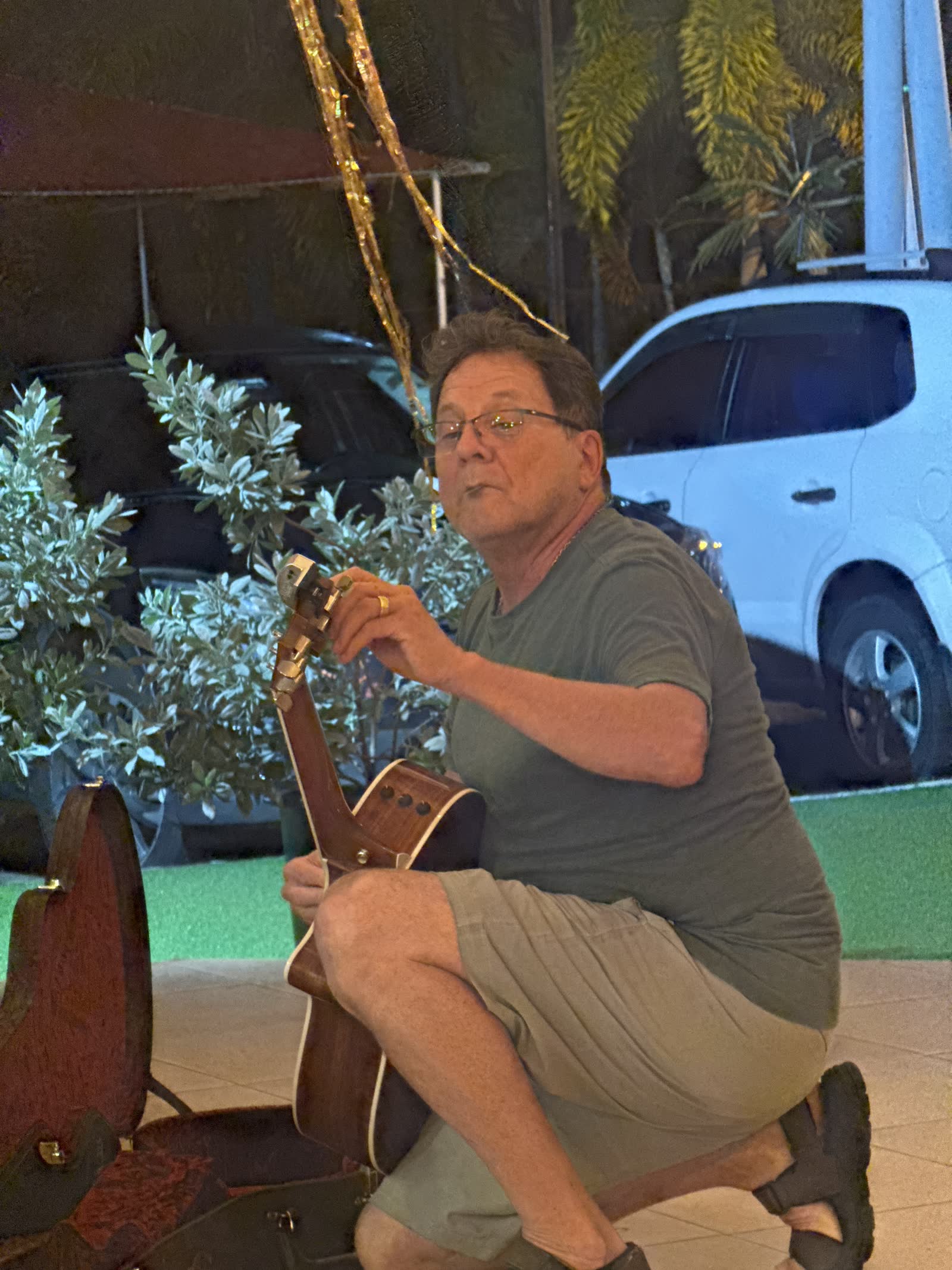 Foto real de la noche de karaoke — músico afinando su guitarra acústica en la terraza de La Divina Commedia Coronado